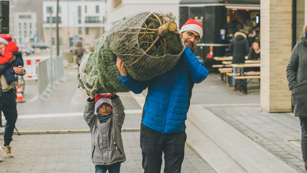 Ein Mann und sein Sohn tragen einen Weihnachtsbaum