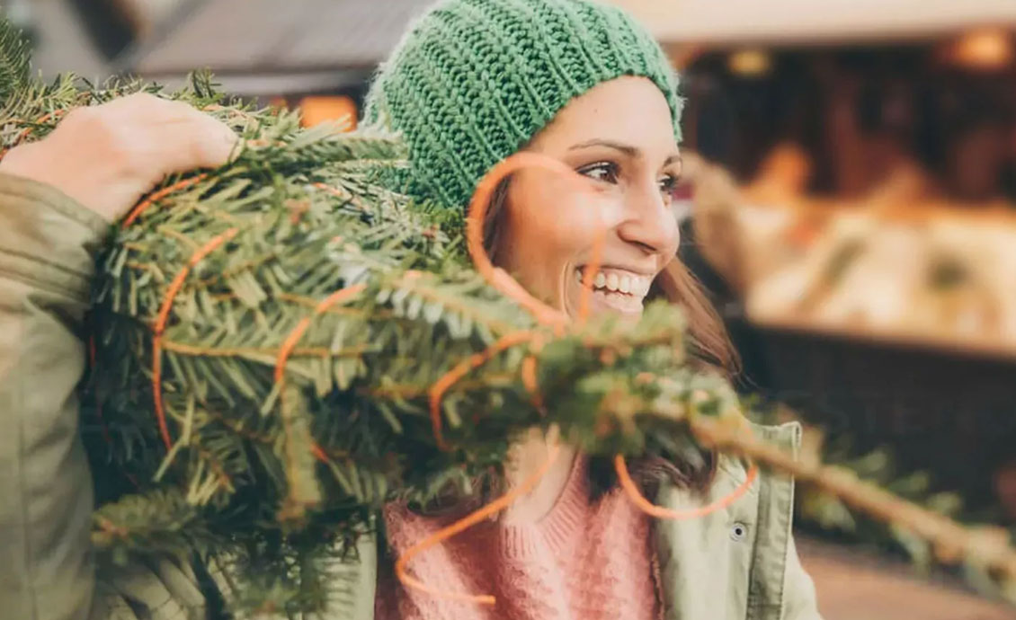 Frau mit Tannnenbaum im Netz auf dem Arm